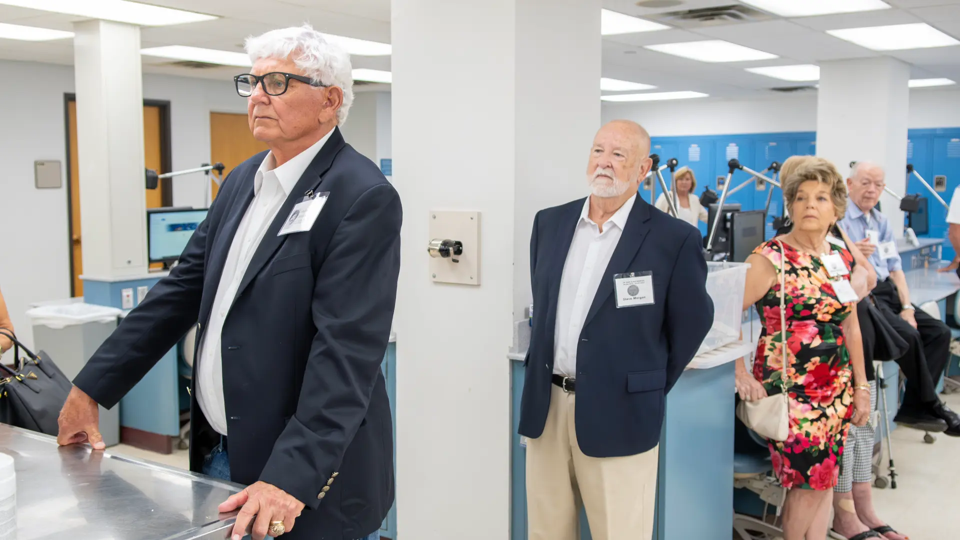 Group of men and women listening to a speaker at a dental school class reunion.