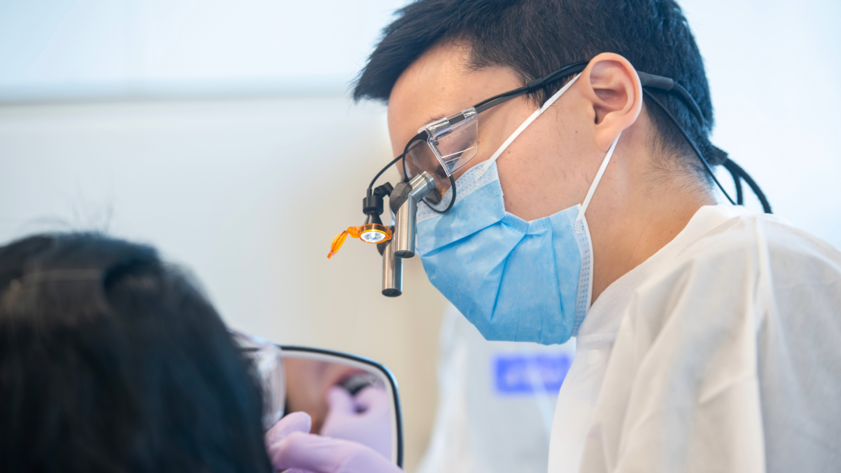 Dentist wearing magnifying loupes treating a patient.