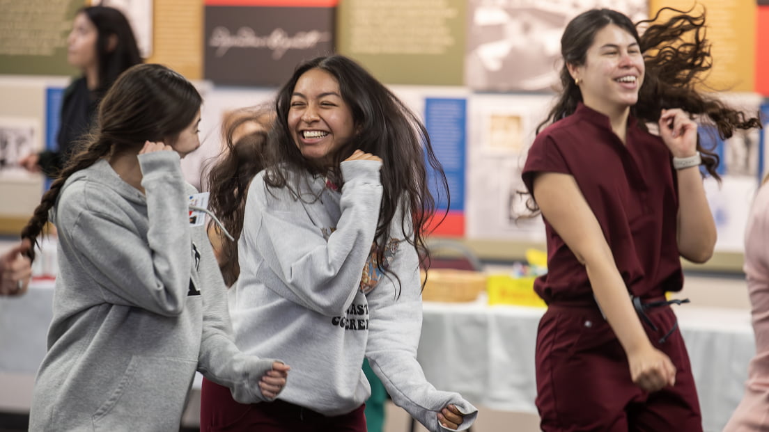 A group of dental students laughing and celebrating together enthusiastically during a campus event.