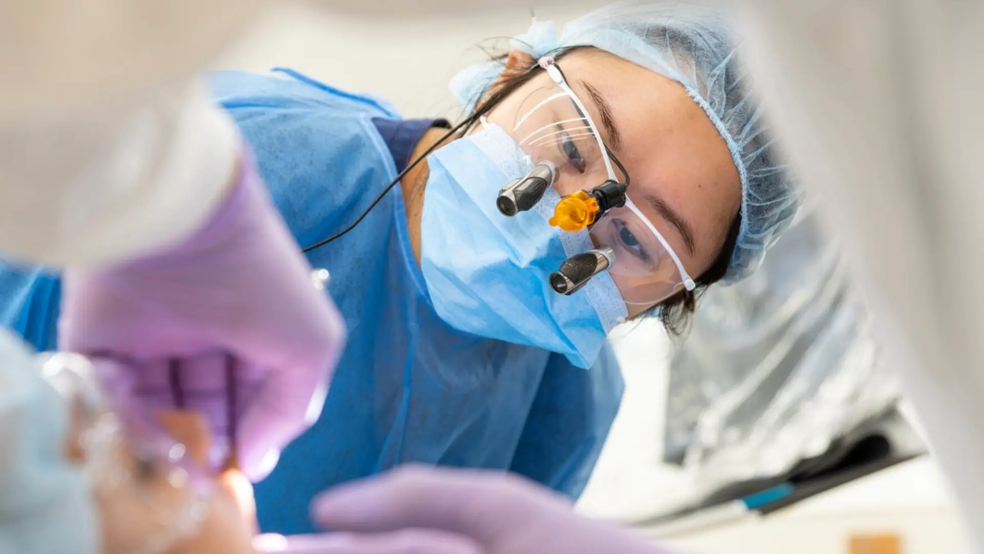 Fourth year dental student in proper PPE observing patient treatment.