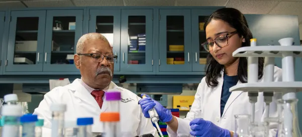 Two researchers in white lab coats working in a laboratory handling samples